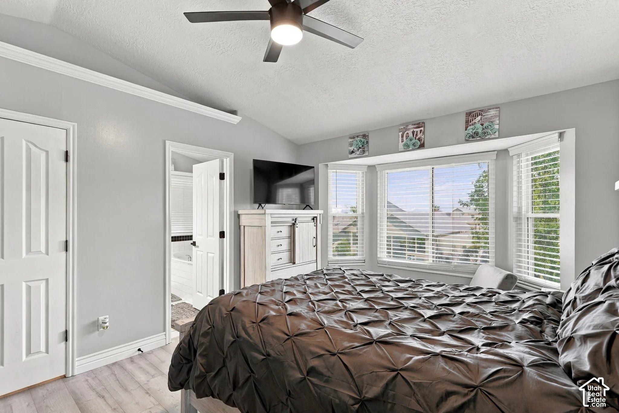 Recessed bay window, light wood-finish flooring, ceiling fan, white paneled doors, and crown molding