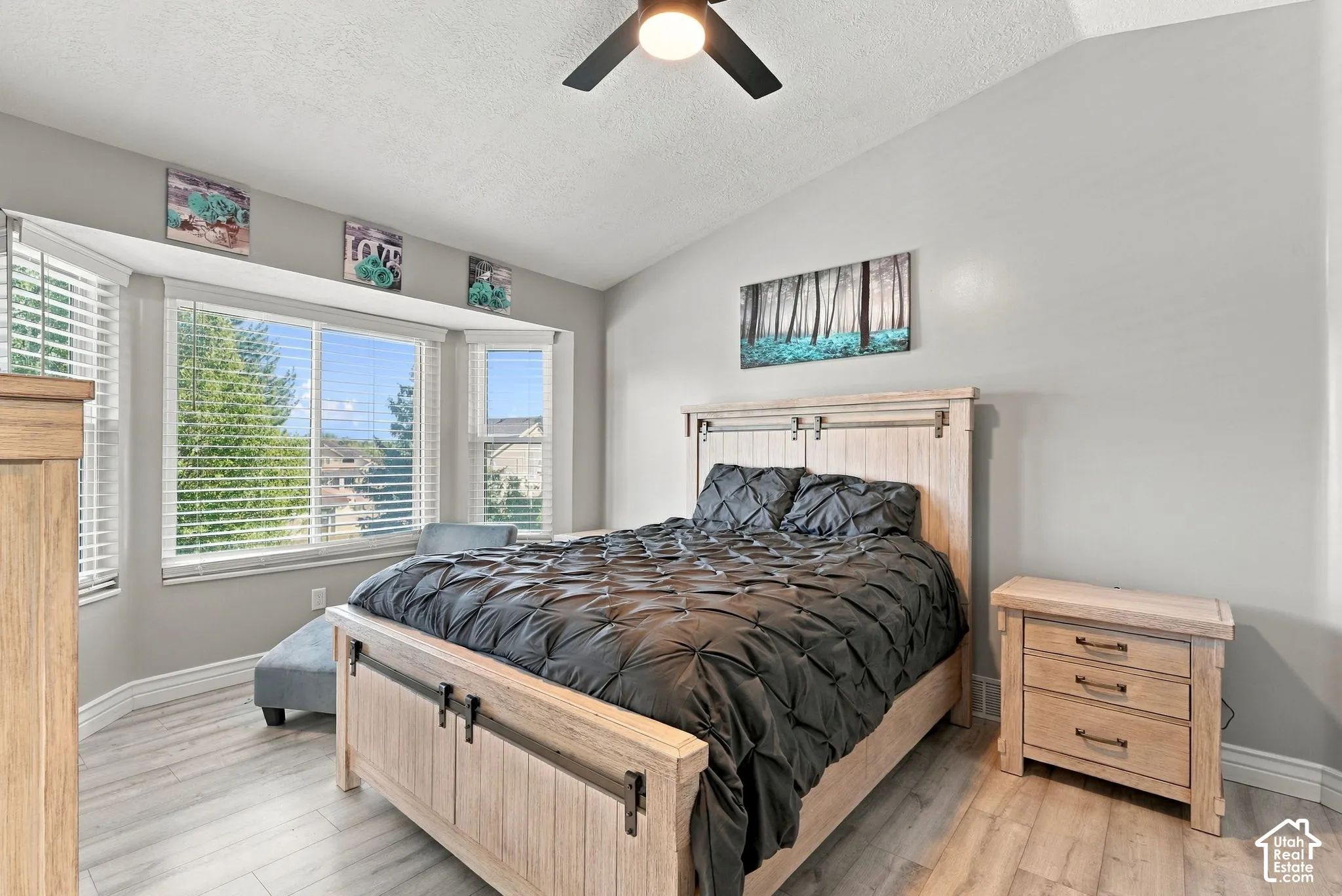 Wood-finish flooring, vaulted ceiling, bay window, ceiling fan, and light gray wall finish