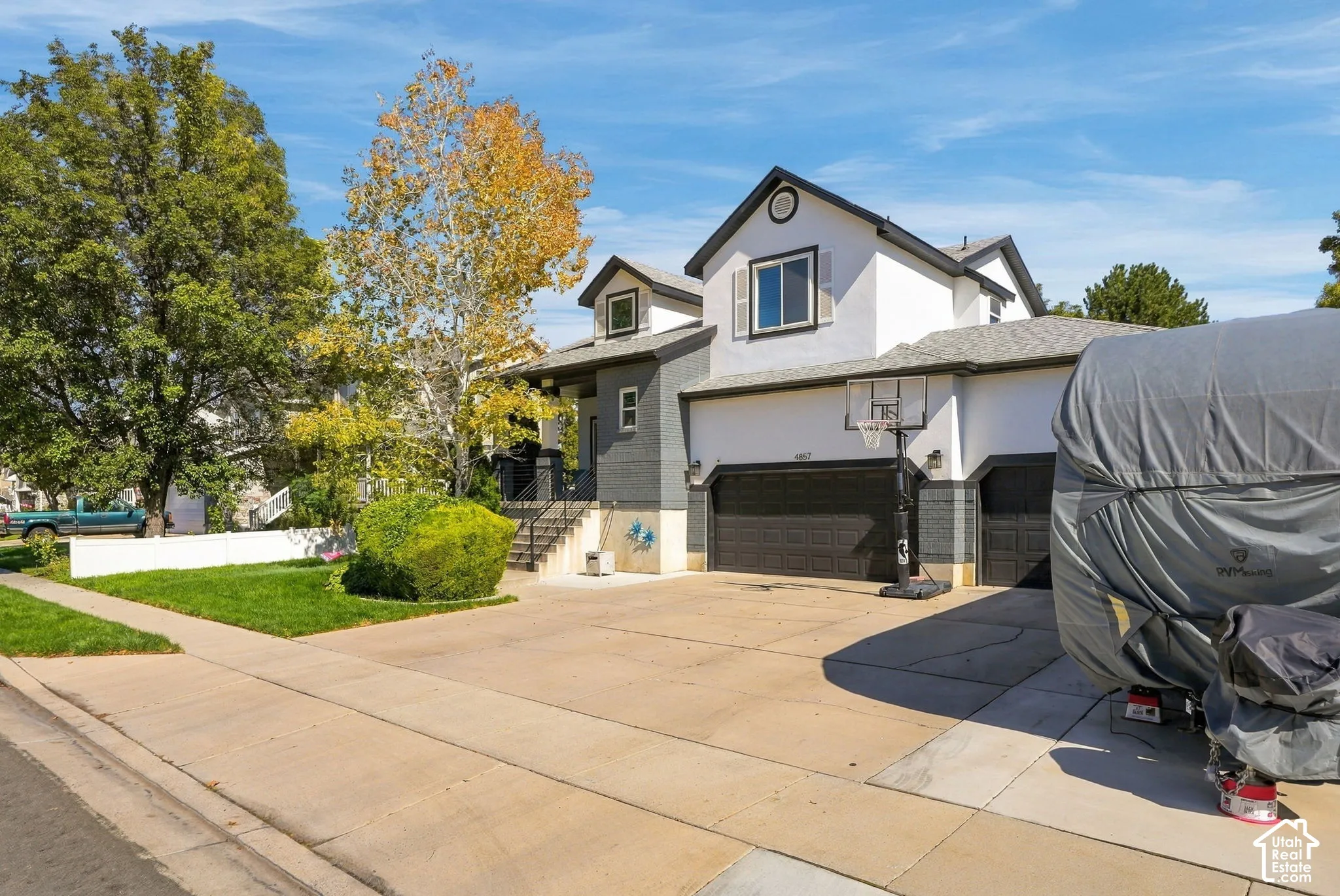 Two-story residence featuring a two-car garage, dormer window, and mature landscaping