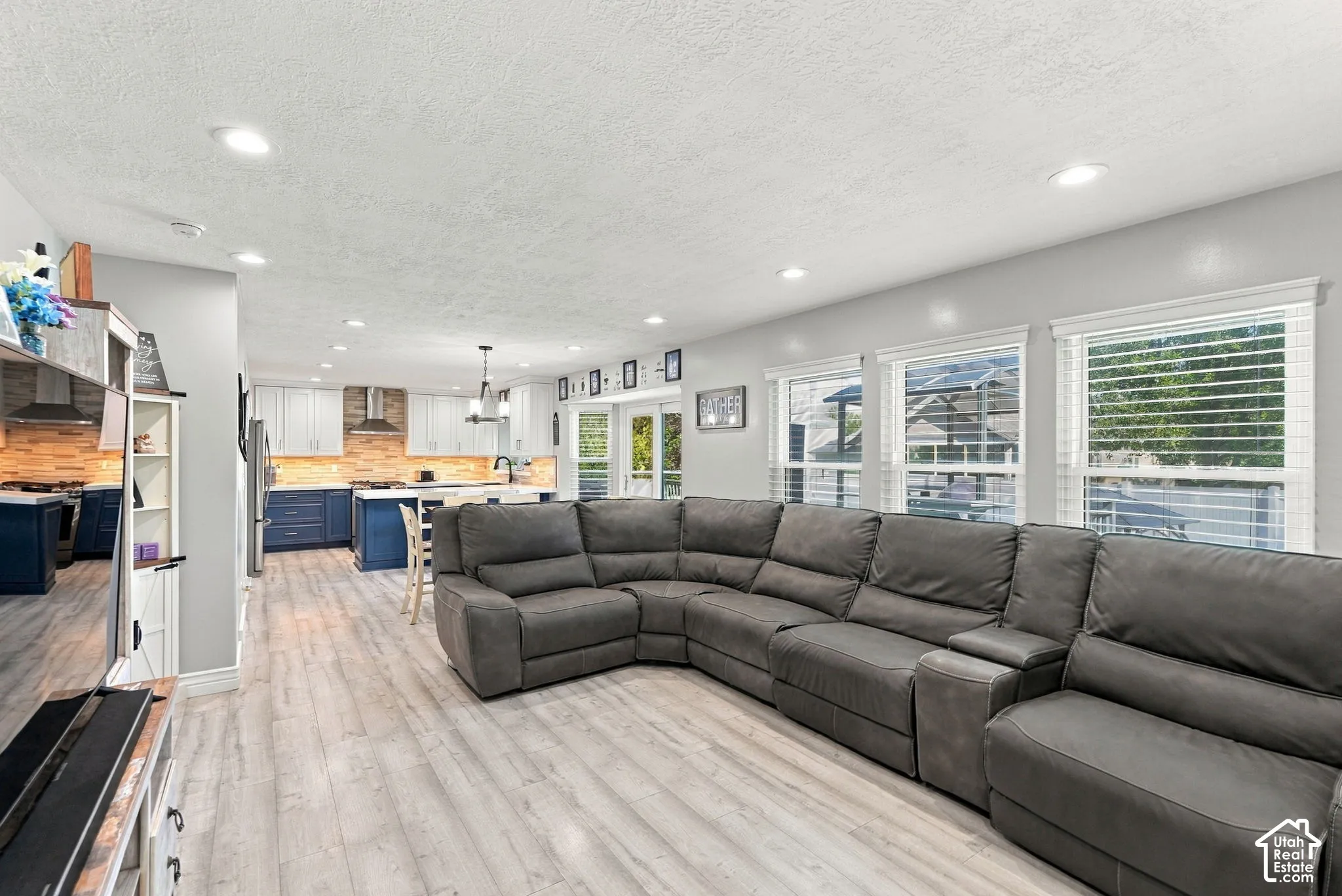 Open-concept living area featuring light wood-finish flooring, recessed lighting, and multiple windows