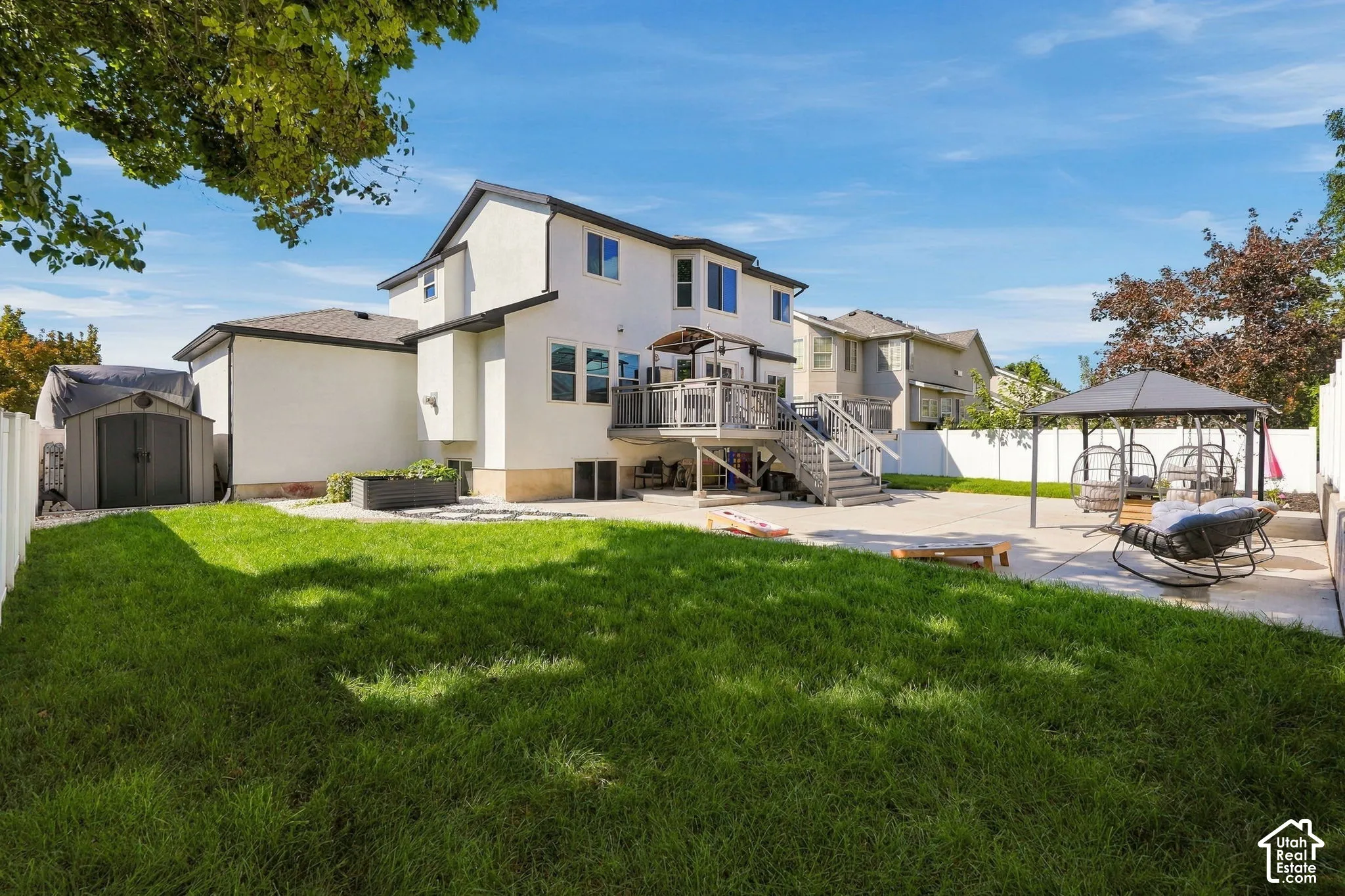 Expansive backyard with a manicured lawn, concrete patio, multi-level deck, and privacy fencing