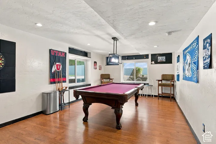 Recreation room featuring wood-finish flooring, recessed lighting, and a suspended light fixture