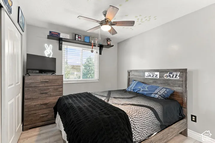 Window with blinds, wood-finish flooring, ceiling fan, and painted walls
