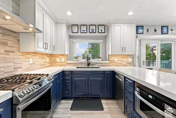 Two-tone cabinetry, stainless steel range, built-in microwave, wood-finish backsplash, and light countertops