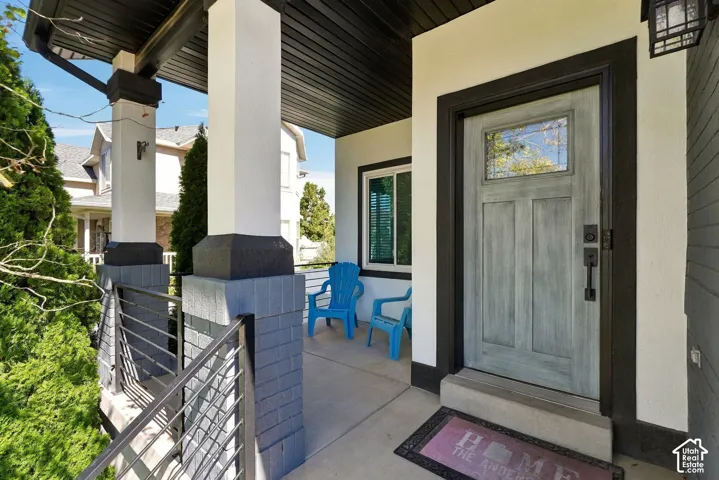 Covered porch featuring a paneled entry door with transom window, white columns, and dark trim