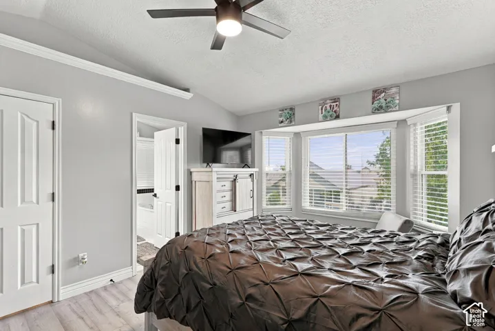 Recessed bay window, light wood-finish flooring, ceiling fan, white paneled doors, and crown molding