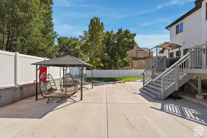 Expansive concrete patio with a permanent gazebo structure, privacy fencing, and a multi-level deck with stairs