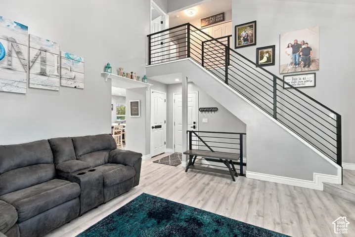 Two-story entrance featuring a contemporary metal railing staircase, light wood-finish flooring, and a vaulted ceiling