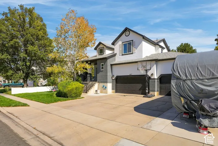 Two-story residence featuring a two-car garage, dormer window, and mature landscaping