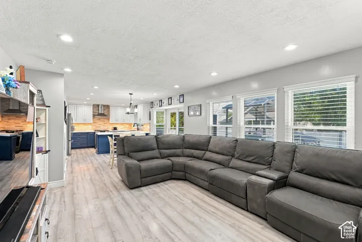 Open-concept living area featuring light wood-finish flooring, recessed lighting, and multiple windows