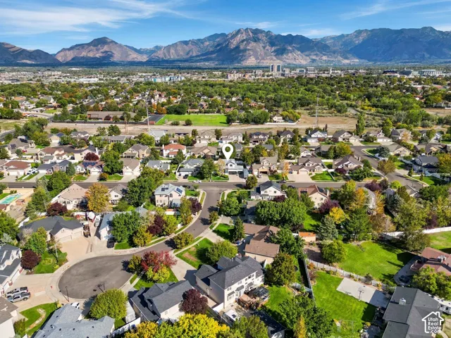 Neighborhood setting with mature trees, established residential properties, and distant mountain backdrops