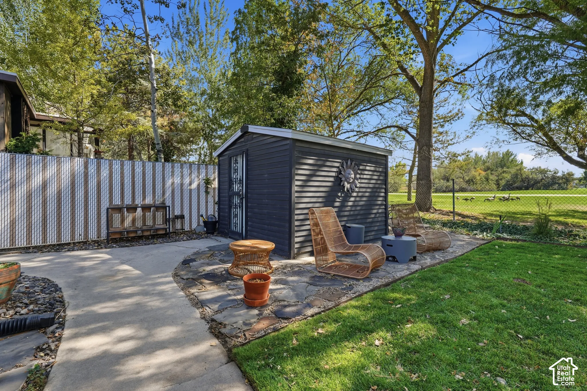 Modern dark-finished garden structure with board-and-batten siding, positioned on a stone-paver patio