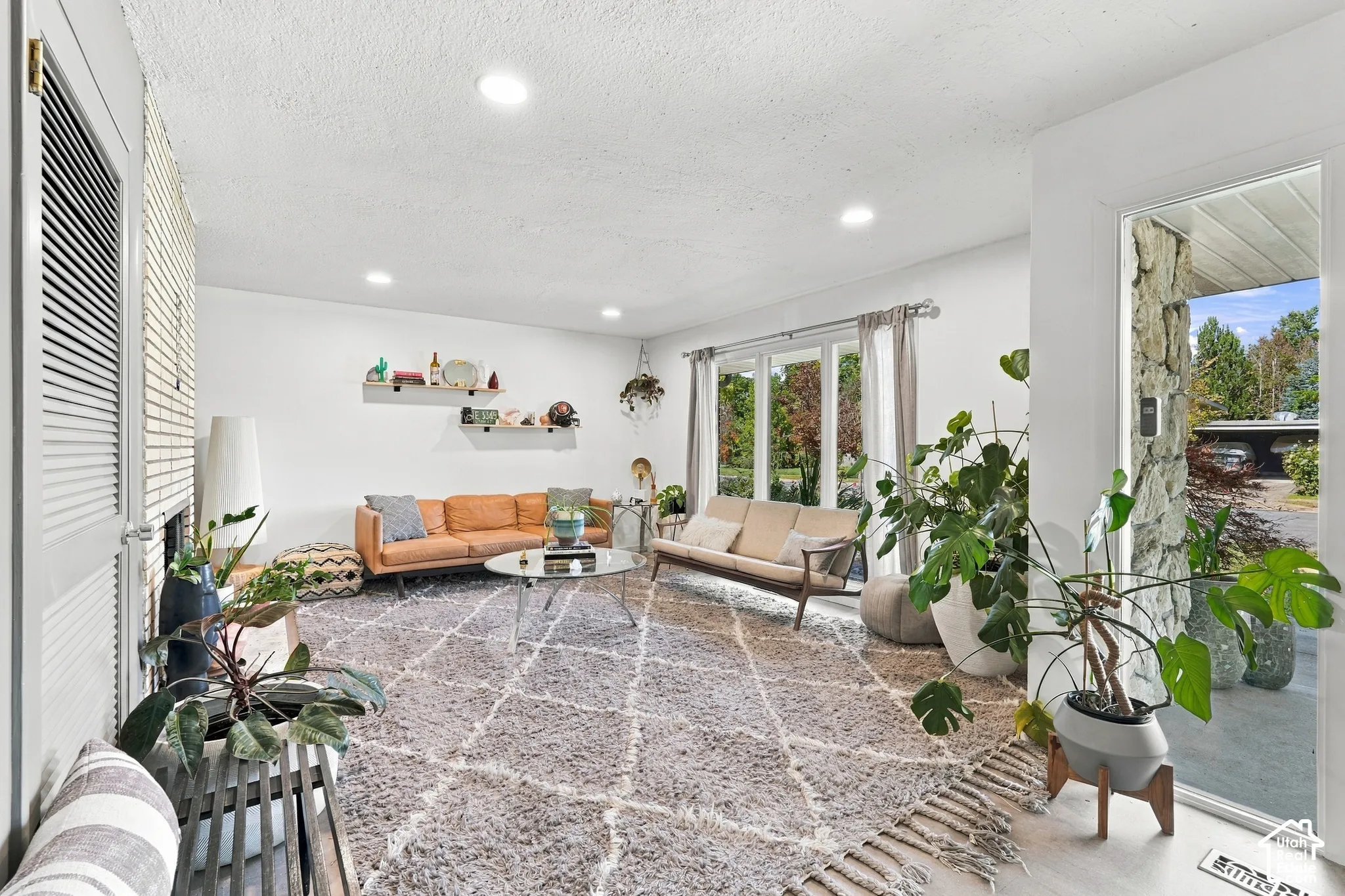 Recessed lighting illuminating the living area, featuring multiple large windows and white walls