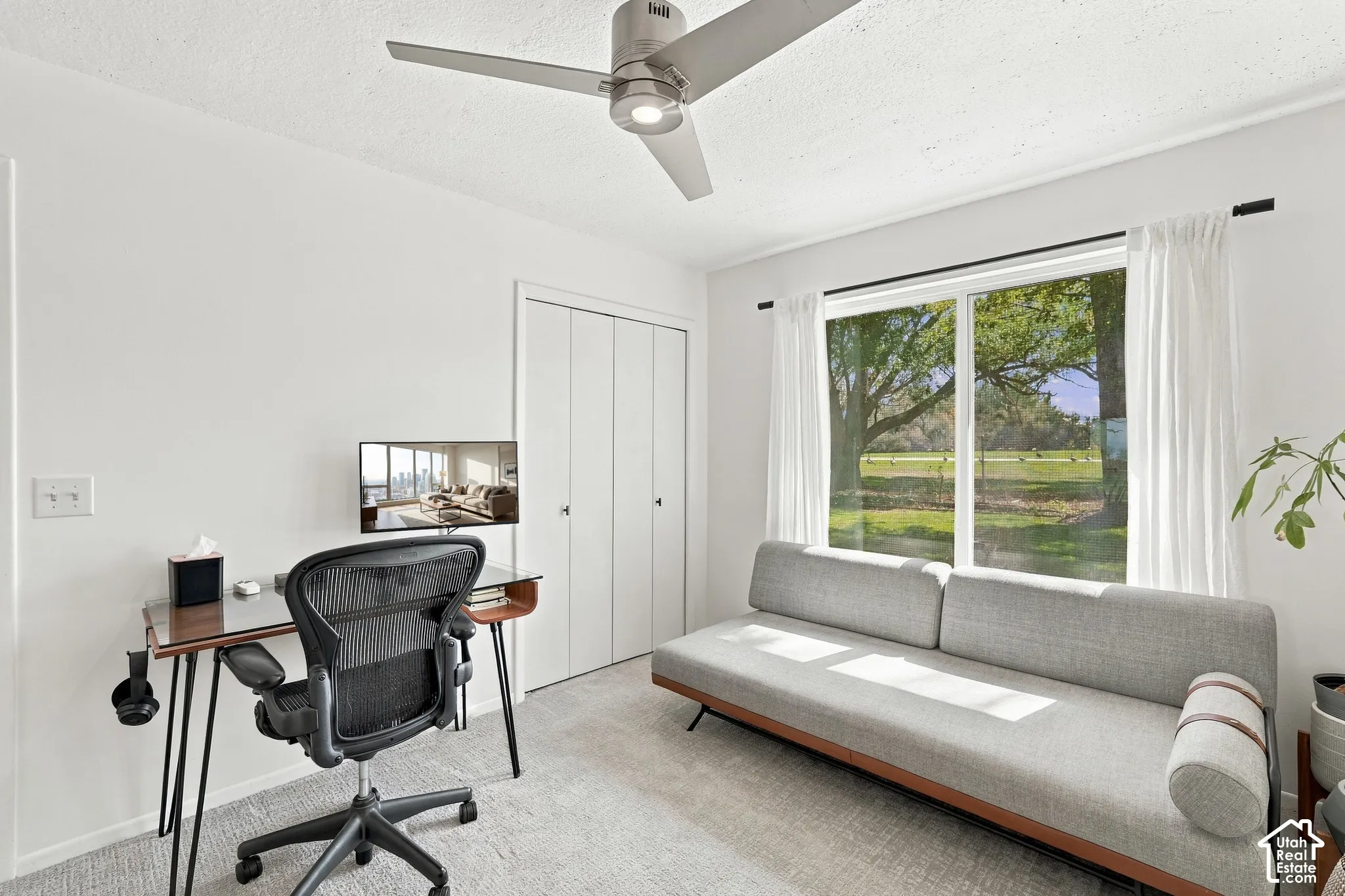 Full-height picture window, textured carpeting, integrated ceiling fan, and bi-fold closet doors