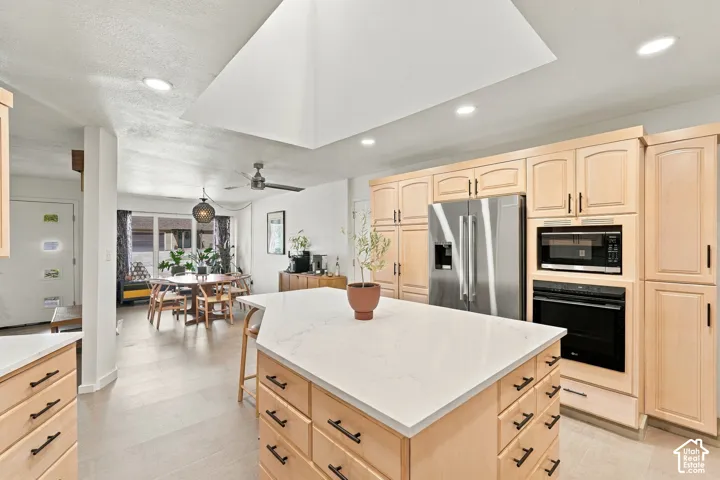 Kitchen featuring light wood cabinetry, stainless steel appliances, a center island with a light-colored countertop, and recessed lighting