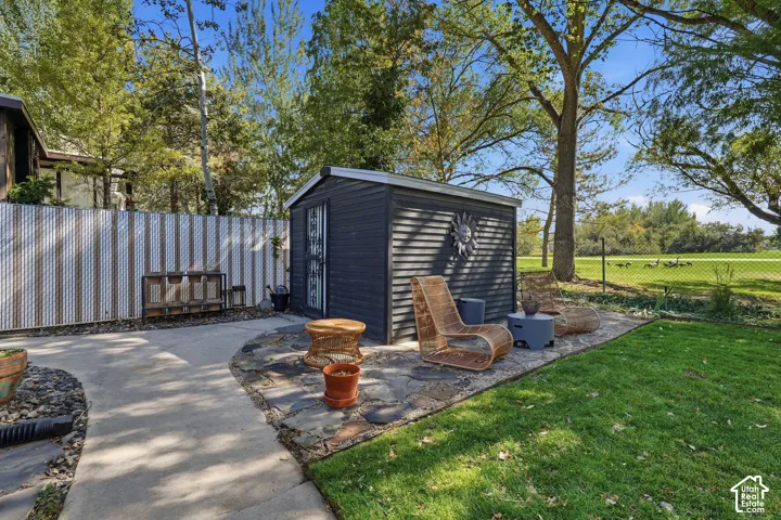 Modern dark-finished garden structure with board-and-batten siding, positioned on a stone-paver patio