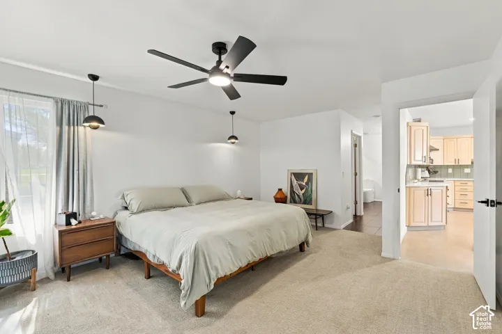 Integrated ceiling fan, twin pendant lighting fixtures, light-toned carpet flooring, and a window with curtain rods