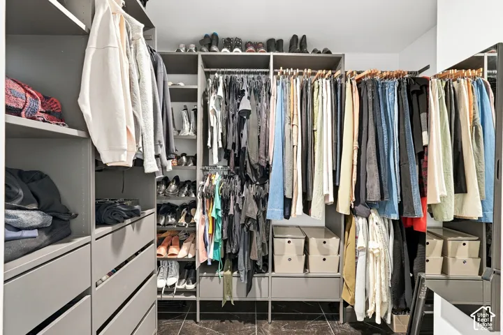 Custom closet system featuring multiple hanging rods, open shelving, integrated drawers, and a dark-toned flooring