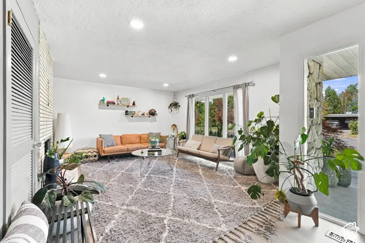 Recessed lighting illuminating the living area, featuring multiple large windows and white walls