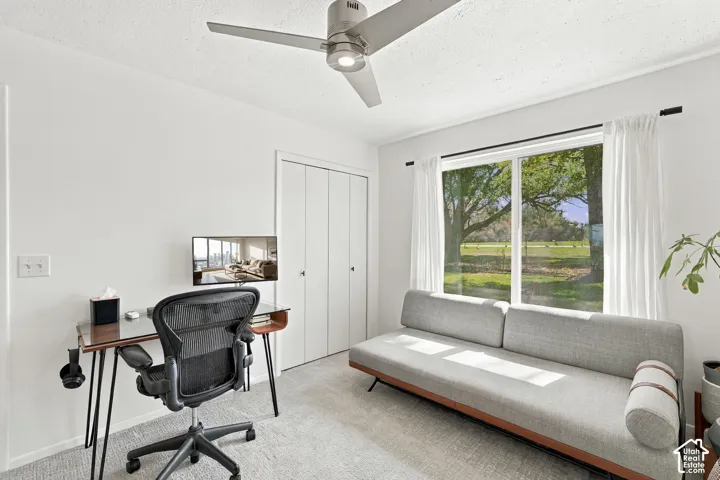 Full-height picture window, textured carpeting, integrated ceiling fan, and bi-fold closet doors