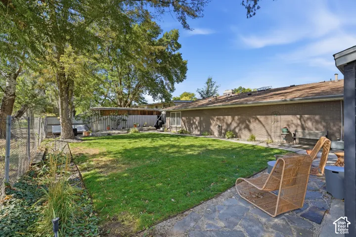 Expansive backyard with a manicured lawn, flagstone patio, and mature trees