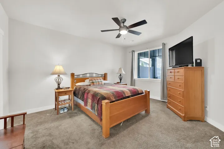 Neutral wall paint, ceiling fan with light fixture, window with white trim, and carpeted flooring