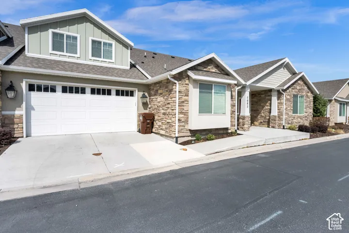 Exterior featuring stone and siding finishes, a two-car garage with transom windows, and an upper-level dormer with dual windows