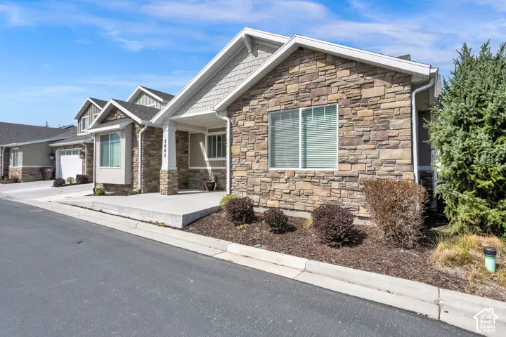 Stone veneer exterior with shake siding accents, covered entry porch, and concrete walkway