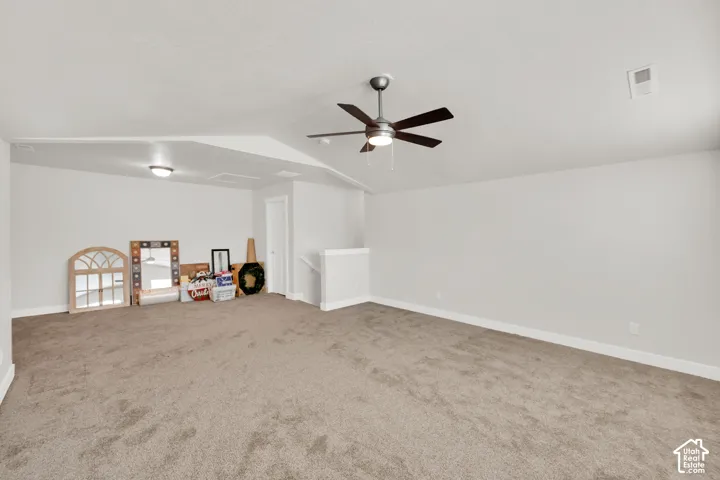 Spacious carpeted room featuring a ceiling fan, recessed lighting, and a white interior door