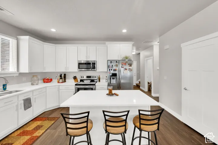 White kitchen cabinetry with stainless steel appliances, white countertops, and a central island