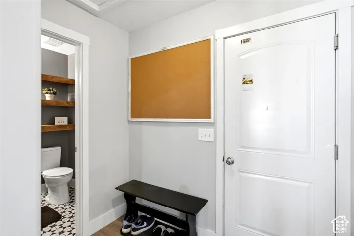 White paneled entry door with chrome hardware, wood-finish flooring, and light gray wall paint