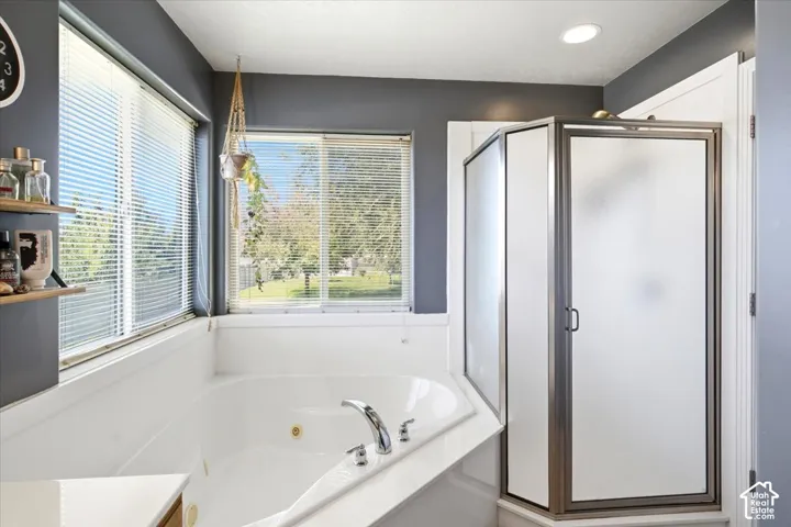 Corner jetted tub with chrome fixtures, adjacent to a frosted glass shower enclosure