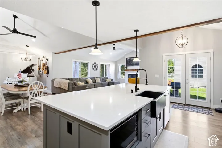 White quartz countertops, black farmhouse sink, matte black faucet, wood-finish flooring, and vaulted ceilings