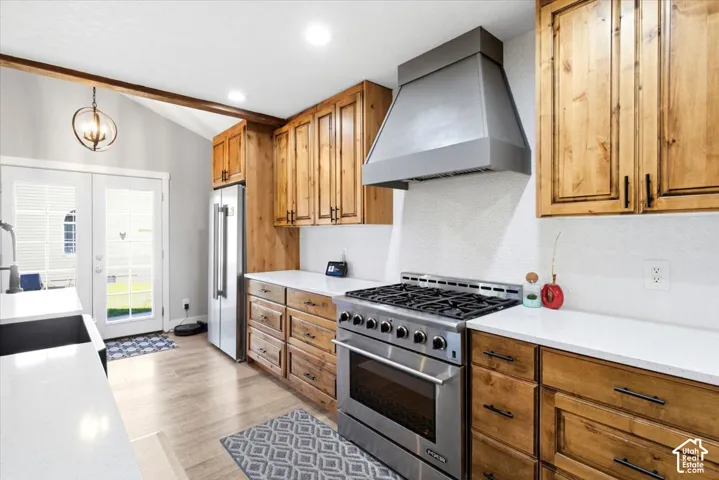 Wood-finish flooring, white countertops, natural wood cabinetry, stainless steel appliances, and a vaulted ceiling with exposed beam