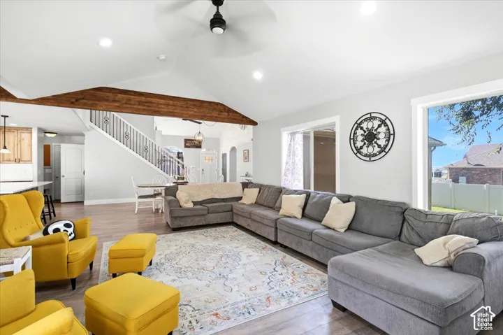 Spacious living area featuring exposed wood beams, vaulted ceiling, wood-finish flooring, recessed lighting, and large windows