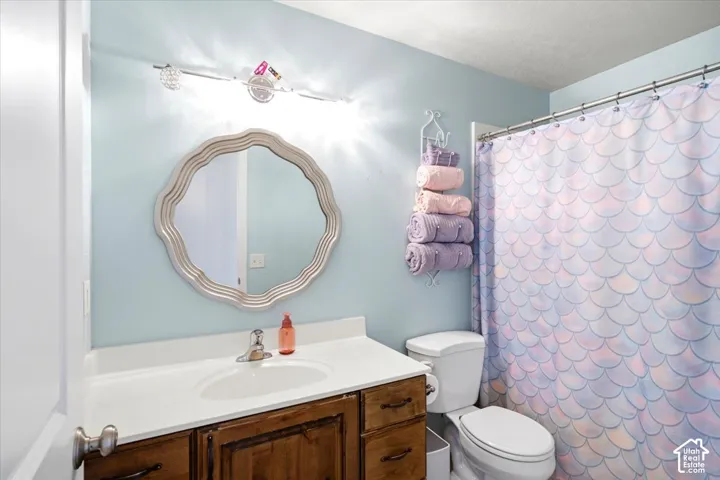 Vanity with a white countertop and integrated sink, chrome faucet, and wood-finish cabinetry