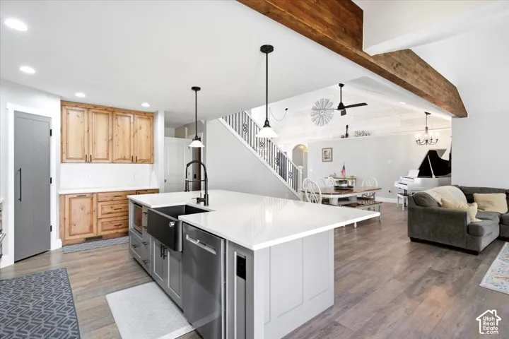 Kitchen island with white countertop and farmhouse sink, wood-finish flooring, natural wood cabinetry, vaulted ceiling with exposed beam, and recessed lighting