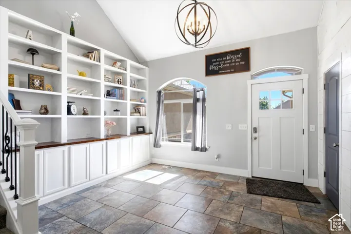 Built-in shelving with lower cabinetry, arched windows, a multi-pane entry door, and large format floor tiles