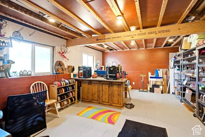 Exposed ceiling joists with recessed lighting, two windows, and durable concrete flooring
