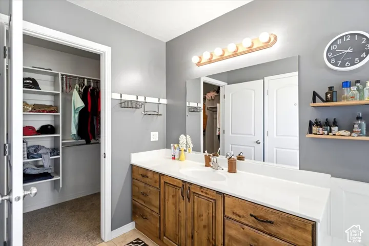 Dual sink vanity with wood-finish cabinetry, white countertop, and expansive mirror