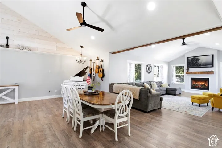 Vaulted ceilings with exposed beams, wood-finish flooring, a built-in fireplace with a hearth, and recessed lighting