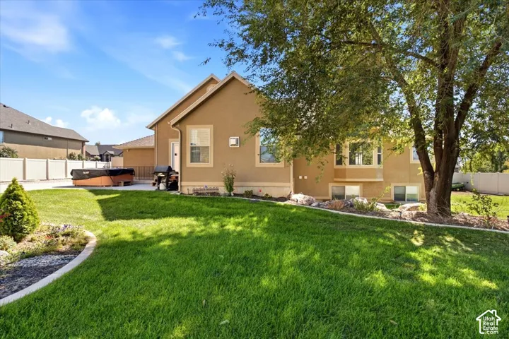 Expansive backyard featuring a manicured lawn, established landscaping, and a paved patio area