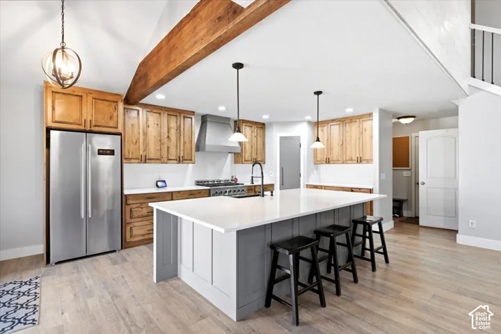 Kitchen featuring wood-finish cabinetry, stainless steel appliances, a center island with seating, and wood-finish flooring