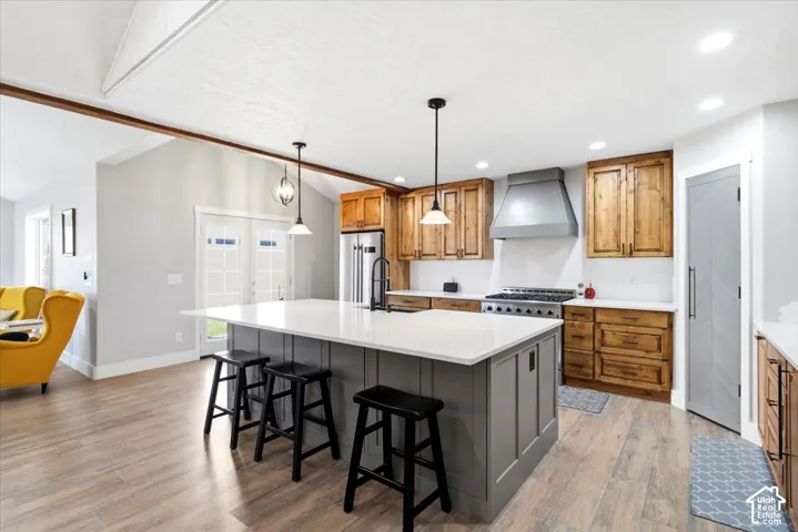 Kitchen featuring a central island with white countertop, stainless steel appliances, wood-finish cabinetry, and wood-finish flooring