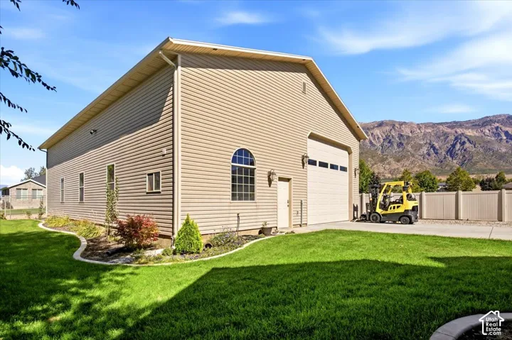 Detached garage structure with siding exterior, large bay door, arched window, and concrete driveway