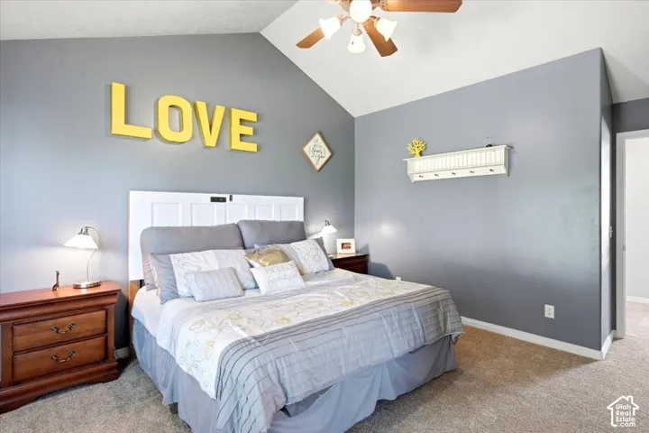 Vaulted ceiling with a ceiling fan, neutral wall color, and carpet flooring