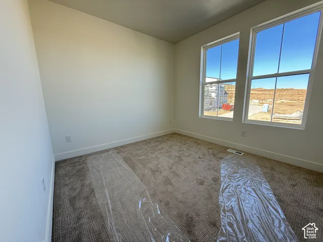 Bright room featuring two large windows, neutral-toned carpet, and white walls