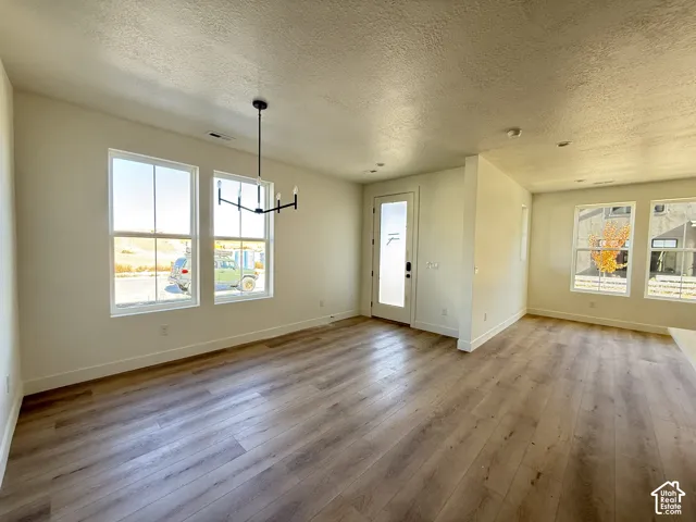 Spacious room featuring wood-finish flooring, multiple large windows, a modern black chandelier, and recessed lighting