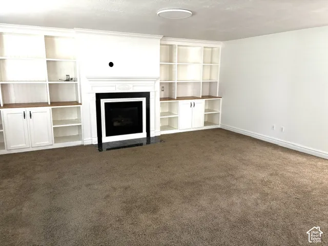 Built-in shelving units, integrated fireplace, white cabinetry, wood-finish countertops, and recessed lighting