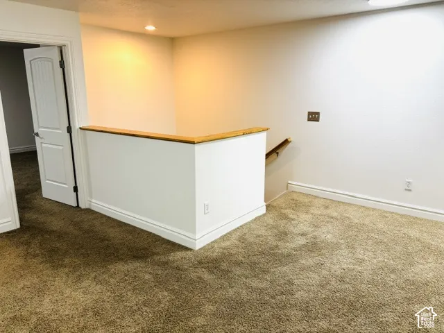 Carpeted interior with white walls, a wood-capped half wall, and recessed lighting